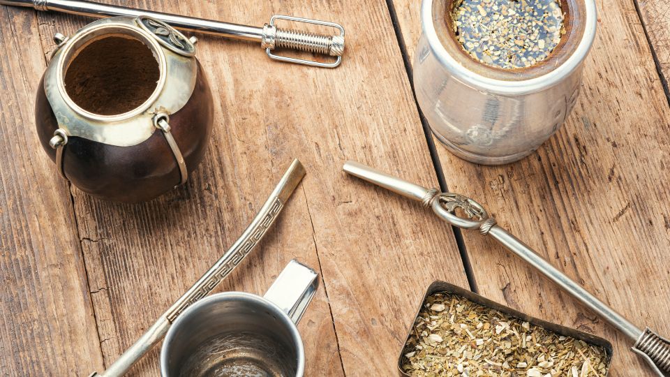 Traditional yerba mate setup with gourds, bombillas, and loose leaves on a rustic wooden table