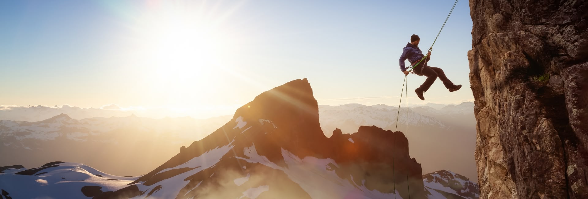 Person rock climbing on mountain during sunrise representing energy and focus with Teko Boost Yerba Mate